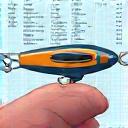 Icon illustrating a finished lure being held in a hand over a blueprint.