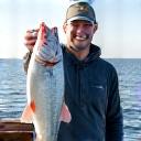 A happy angler proudly holding a large Bream on a boat deck.